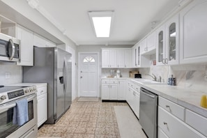 This culinary haven features pristine white-painted cupboards that gleam with timeless elegance, creating an airy and inviting atmosphere.