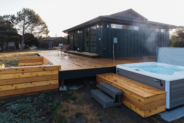 The hot tub and fire pit are both on the ocean side of the house at Moran Shores