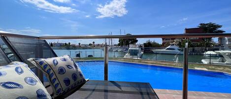 tumbonas y vistas a la piscina y los canales  desde la terraza del apartamento