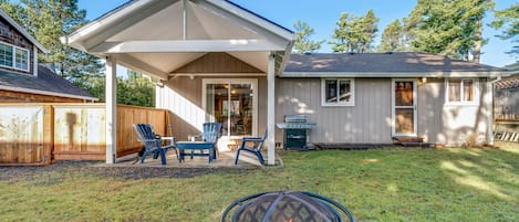 Backyard with covered patio with seating, BBQ and a firepit