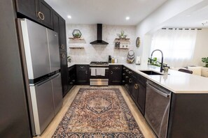 Cook in our glam kitchen with black cabinets, gold accents, and modern tools.