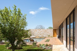 Blick auf den großen Swimmingpool mit Liegestühlen zum Ausruhen und Entspannen in der berühmten, klimatisierten Luxusvilla Serenity Pula in Istrien zur Miete, umgeben von viel Grün