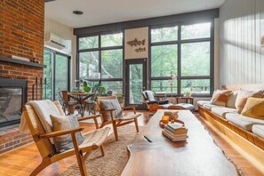 Our midcentury zen-like living room with a wall of windows leading to your very own deck in the treetop canopy.