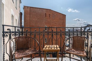 Charming balcony featuring two wicker chairs and a decorative wrought-iron railing, perfect for morning coffee.

