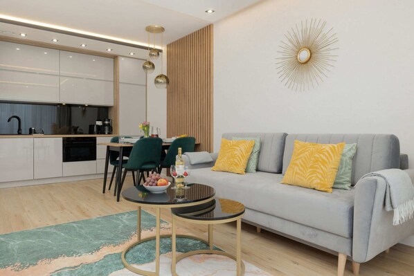 Stylish living room featuring a gray sofa with yellow accent pillows, a modern dining area, and sleek decor.

