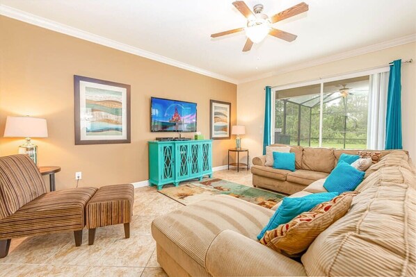 A living room  is outfitted with comfortable seating across from a large Smart TV with cable channels