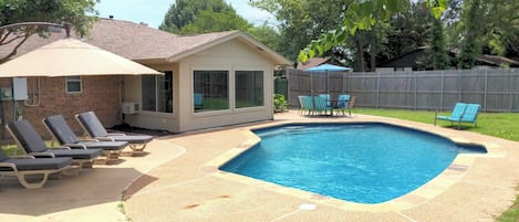 Back yard, including pool, loungers, umbrellas, table, and seating.