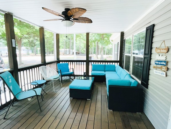 Screened in porch with plenty of seating, a fan, & strip lights for night.