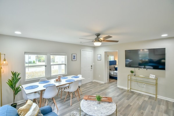 Living room with 65" Roku smart TV, chaise couch, and dining table
