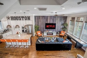 Living room with remote fireplace, black velvet sectional providing plenty of seating, tiger rug, a 4K Roku 75" Television,  LED Atomic 9 ft shuffleboard with an open concept perfect for entertaining.