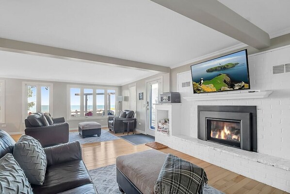 Large open space main floor with fireplace, TV and gorgeous views of the water from large bank of windows.