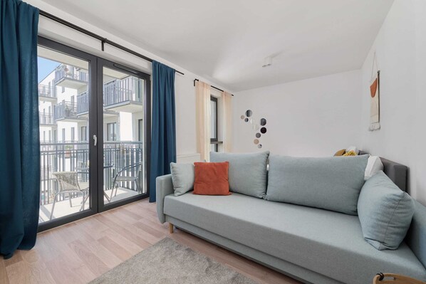 Spacious living room with a comfortable gray sofa, large windows, and stylish decor.


