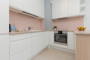 Fully equipped kitchen with white cabinetry, pink backsplash, and modern appliances.

