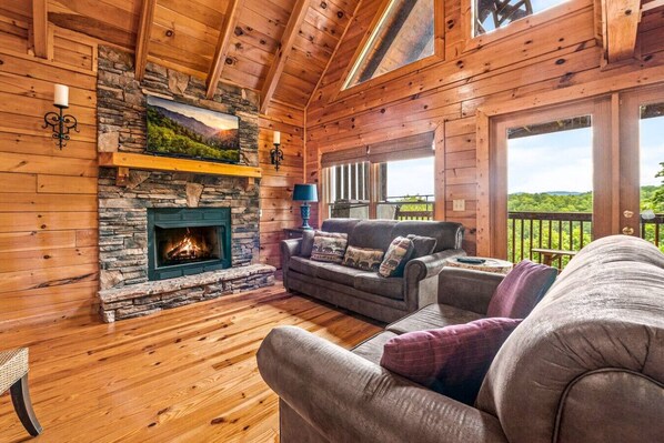 Cozy living room with gas fireplace, comfortable furniture, large windows and high ceilings.