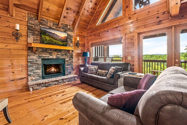 Cozy living room with gas fireplace, comfortable furniture, large windows and high ceilings.