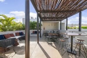 Rooftop with shaded seating, high tables, and lounge benches to relax.
