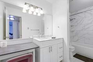 2nd bathroom has vanity with chair + Shower Tub