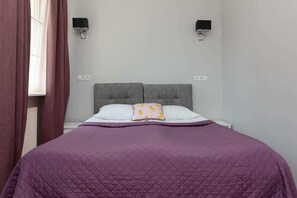 A cozy bedroom featuring a double bed with purple bedding, bedside tables, and soft lighting for a restful ambiance.