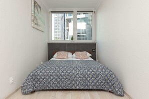 Comfortable bedroom with a double bed, patterned bedding, and large windows for natural light.