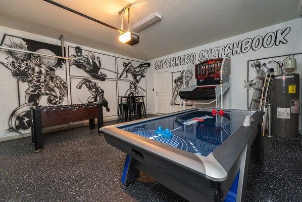 Unleash your inner hero in this superhero-themed game room with air hockey, foosball, and basketball arcade fun!