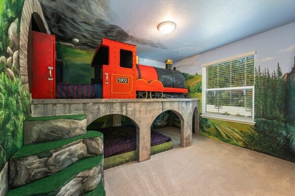 All aboard the adventure express! This train-themed room offers a magical escape for kids with bunk beds and scenic murals.