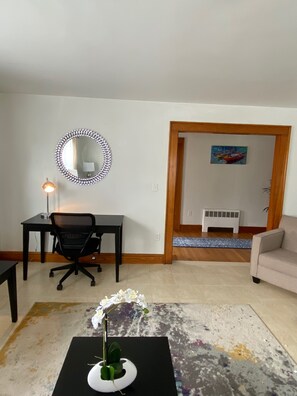 Writing desk with lamp and ergonomic chair in living room.