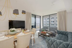 A spacious living and dining area with modern furniture and floor-to-ceiling windows.


