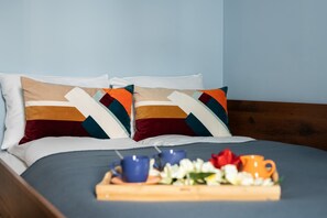 Cozy bedroom with a double bed, colorful accents, and a breakfast tray for a welcoming touch.

