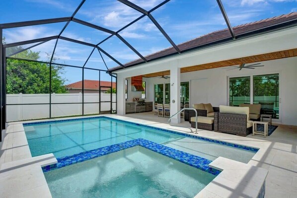 Experience outdoor bliss in our screened pool cage, featuring a heated pool, sun shelf, and above-ground spa for ultimate relaxation