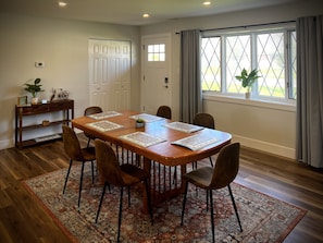 Wooden dining room table, located by a large bay window, is perfect for families