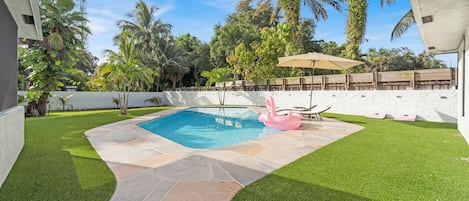 Swimming pool and sun loungers surrounded by palm trees