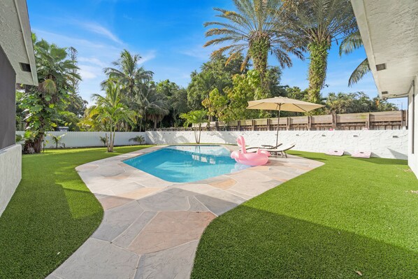 Swimming pool and sun loungers surrounded by palm trees