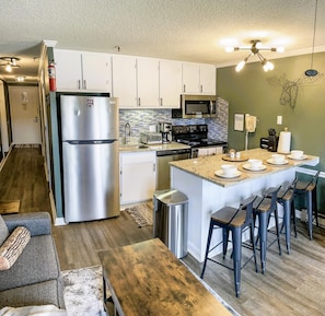 The modern kitchen features granite countertops, stainless steel appliances, and a wine fridge.