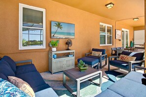 Large covered lanai with outdoor TV and comfortable seating.