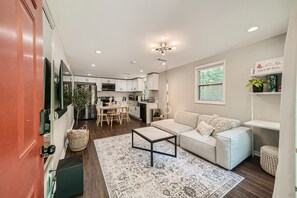 Bright living room with comfortable seating and a desk and large smart tv.