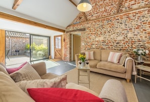 Bromholm Barn, Ridlington: The spacious, open-plan sitting area with beautiful exposed beams and stonework