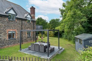 Large garden with outdoor furniture, charcoal barbecue and pergola.