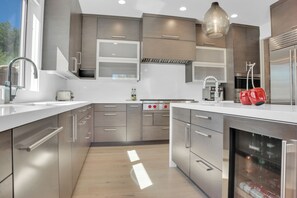 Vacation rental kitchen with medium grain wood cabinets, white counters, and high end appliances.