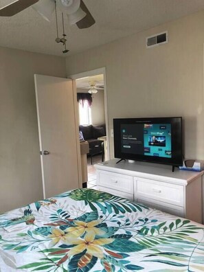 Smart tv and dresser. Bedroom leads to kitchen/living room. 