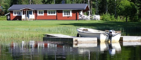 Vy från sjön på bryggan med båten och huset .