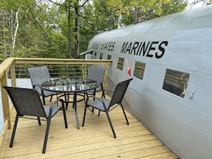 Deck atop left wing overlooking lake with dining set and grill.