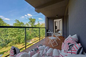 Balcony with cozy seating, overlooking lush greenery, perfect for relaxation.

