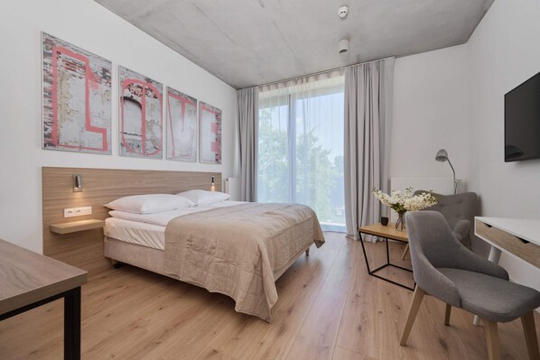 Modern bedroom with a comfortable bed, minimalist decor, and a large window allowing natural light.

