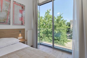 Bright bedroom with a scenic view from a large window, creating a relaxing atmosphere.

