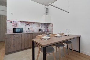Open-plan kitchen and dining space with wooden cabinets and a compact dining table.

