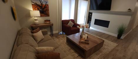 Relax in the stylish living room featuring a sofa sleeper, smart TV, and direct patio access.