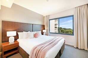 Relax in the spacious second bedroom featuring a king-sized bed and a window that floods the space with natural sunlight.