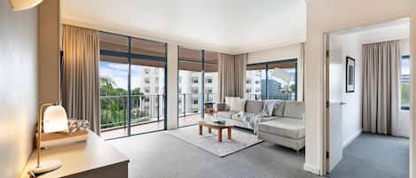 Spacious sun-soaked living room with plush couches and access to the breezy outdoor balcony with views.
