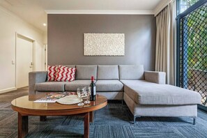 A well-lit living room is complemented by a sleek couch and sliding-door access to an outdoor courtyard