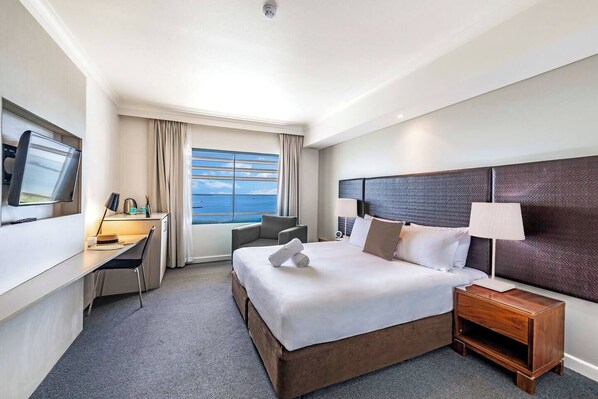 Rays of light stream into the spacious studio through a large window showcasing tranquil views of the sea
